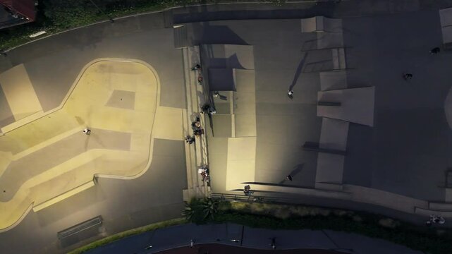 Aerial footage of a skater performing tricks inside a modern skatepark bowl at night.