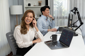 Profile smiling beautiful Asian businesswoman looking camera pose thinking creative project at modern office on working desk casual day. Blurry background man colleague analyzing data on pc. Infobahn.