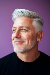 Obraz premium A man with timeless elegance and a natural smile. Idea of style for aging men. Purple solid background. Trendy men's classic long sweep haircut - midlife white man with white hair.