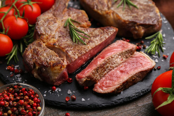 Pieces of delicious beef meat, spices and tomatoes on table, closeup