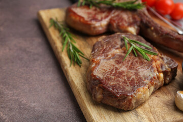 Pieces of delicious beef meat with rosemary on brown table, closeup. Space for text