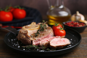 Pieces of delicious beef meat, spices and tomatoes on wooden table, closeup