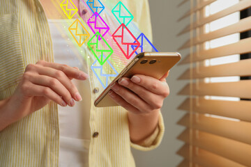 Email message. Woman using smartphone at home, closeup. Envelopes flying out of device
