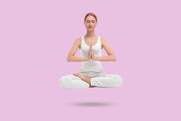 Young woman levitating during meditation on light violet background. Practicing yoga