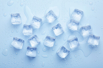 Crystal clear ice cubes on light blue background, flat lay