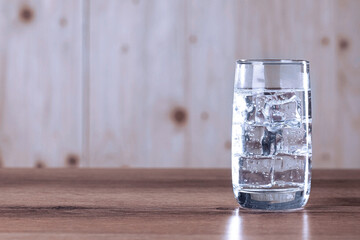 Refreshing soda water with ice cubes in glass on wooden table. Space for text