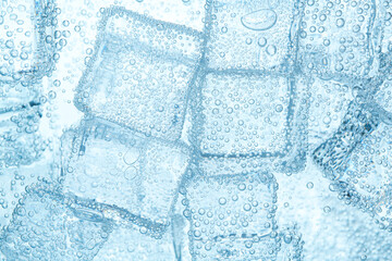 Refreshing soda water with ice cubes as background, closeup