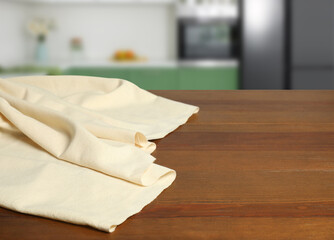 Beige tablecloth on wooden table in kitchen, space for text. Home textile