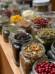 Colorful collection of spices and herbs in glass jars displayed on wooden shelf in a cozy kitchen