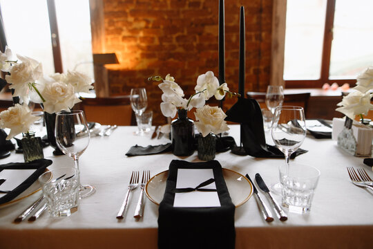 A beautifully arranged dinner table showcasing black candles and white roses, perfect for a special occasion or celebration.
