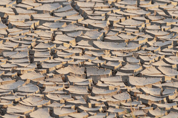 A close up of cracked, parched earth in an arid or drought affected region. The dry, fragmented ground highlights the extreme weather conditions and water scarcity in the area, Namibia Africa.