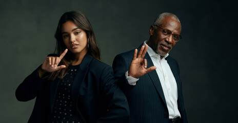Confident hispanic young woman and african mature man in business attire showing hand gestures