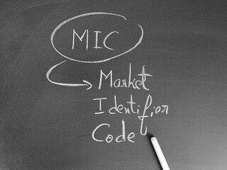 MIC abbreviation meaning Market Identifier Code, is handwritten on a chalkboard with chalk in...