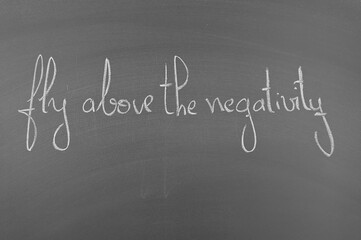 Motivational quote on chalkboard: Fly above negativity. Encouragement to overcome challenges and...