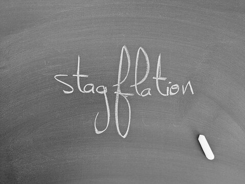 The word "stagflation" is written in chalk on a blackboard next to a piece of chalk, representing economic challenges. - Powered by Adobe