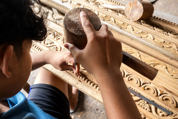 Carpenter carving wood using traditional tools in workshop