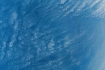 A close-up view of a partly cloudy sky.  Feathery, wispy clouds are scattered across a vibrant blue backdrop
