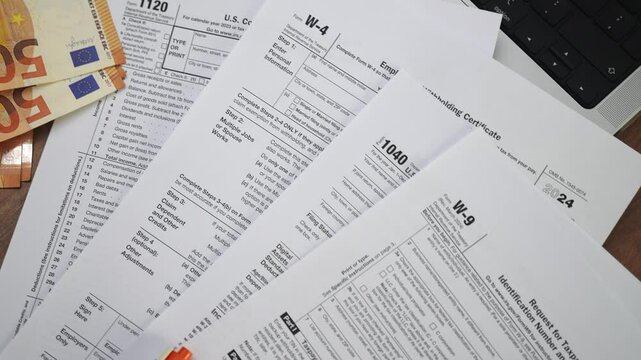 Euro banknotes with several tax declarations spread on wooden table with Request for Taxpayer Identification Number and Certification placed on top slow motion