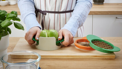 Person using a vegetable cutter to slice green peppers in a bright kitchen setting, focusing on healthy meal preparation.
