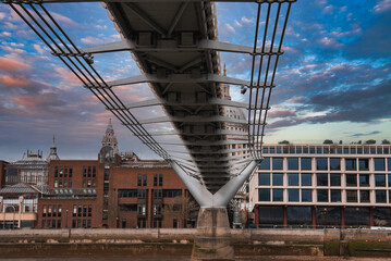 View of the Millennium Bridge's suspension cables and modern design, with St. Paul's Cathedral dome...