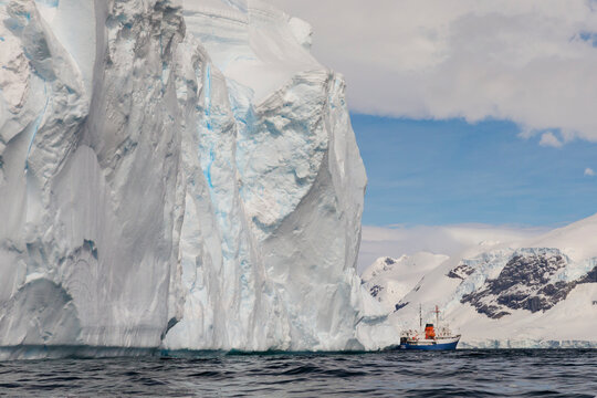 Southern Ocean, Antarctica. Huge weathered tabular icebergs appear to loom over a ship.