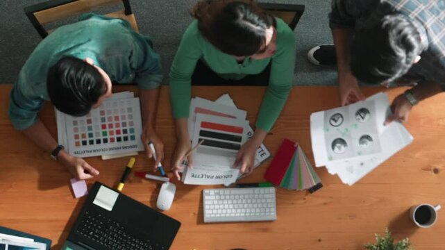 Top view of smart people throw paper and giving high five at meeting table with financial document and stock market analysis paper scattering around. Aerial view of team celebrate project. Symposium.
