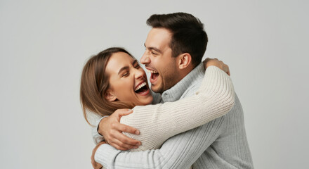 Happy young caucasian couple embracing and laughing joyfully in warm sweaters