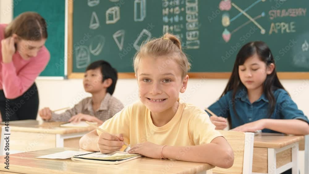 Aufkleber caucasian smart child smiling at camera while doing classwork at classroom while happy multicultural