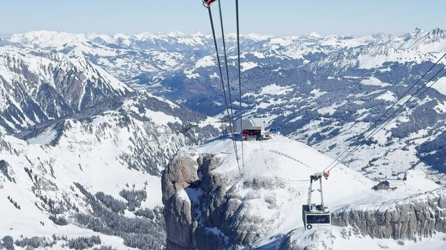 Descending and ascending Glacier 3000 cable cars passing each other with tourists, snowy Alpine peaks, and the Peak Walk bridge in the Swiss Alps
