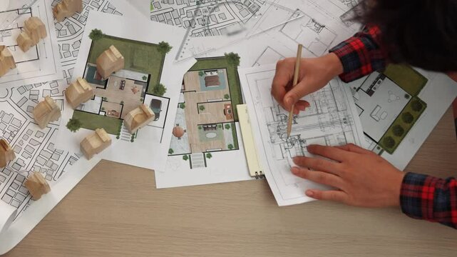 Architect and safety engineer discussion about building construction use blueprint on table with architectural document, measurement tool and wooden block scatter around at modern office. Delineation.