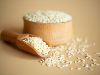 sesame seeds in a wooden bowl on a beige background