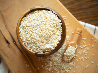 Bowl with sesame seeds and wooden spatula on rustic background