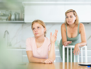Angry mother shouts at teenage daughter. Generational conflict. Sad and distressed girl listens to her mothers claims