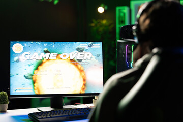 Gamer receiving game over screen, getting his spaceship destroyed in huge explosion while flying in...