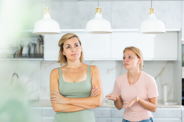 Portrait of upset disappointed woman with teenage daughter calming her, asking to forgive after...