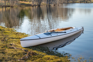 decked expedition canoe with a wooden paddle on a shore of Horsetooth Reservoir in northern...