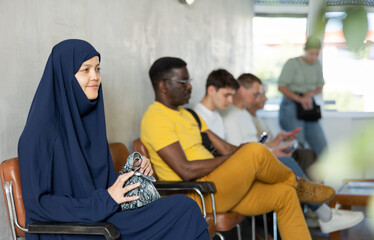 Obraz premium ..Young arab woman waiting for her turn on chair in waiting room..