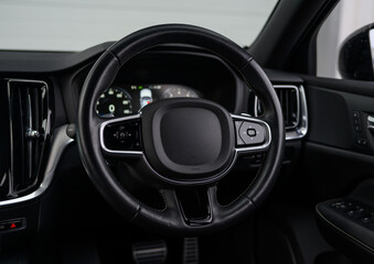 Fototapeta premium The steering wheel of a car is black and has a black center