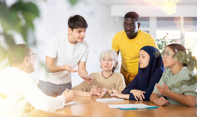Group of multinational people making notes in documents at table in office