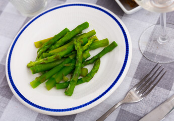 Fresh green asparagus with sunflower oil on a white plate