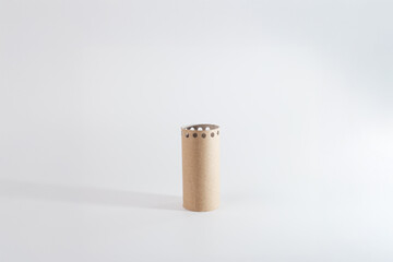 a simple cardboard tube standing upright on a plain surface. Around the top edge of the tube,...