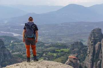 Hiking tourist enjoying scenic view of landscape seen from the famous rock formations of Meteora, Kalambaka, Thessaly, Greece