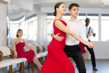 Energy man and Asian woman are dancing classic version of waltz in couple during lesson at studio....