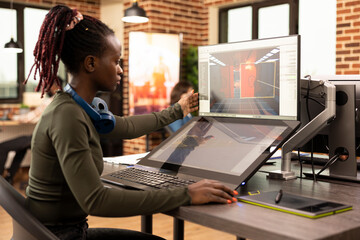African American digital artist analyzing a creative project on desktop screen in a startup company. Black female employee looking at screen, working on her designs at the production department office