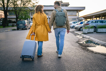 back view of woman and man traveler dragging grey suitcase outdoor
