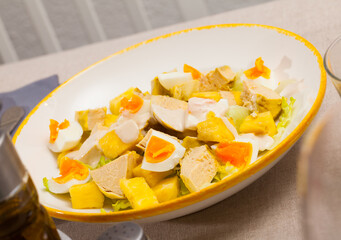 Piquant salad of chicken fillet, canned pineapple, fresh lettuce and eggs served on white plate..