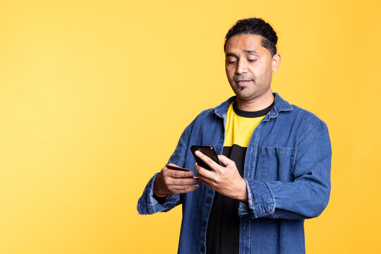 Indian man adding payment method on online website with his card, delighted to take advantage of promotions in the studio. Young person thrilled to do internet shopping, typing credit card data.