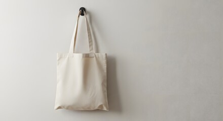 Plain cotton tote bag hanging on a wall hook. Minimalist eco-friendly accessory, ideal for reusable shopping, branding mockups, or sustainable lifestyle visuals.