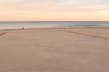 Empty sea beach with yellow sand. Pink sunset over the sea. The coast in the evening at the resort. Alicante, Costa Blanca, Spain