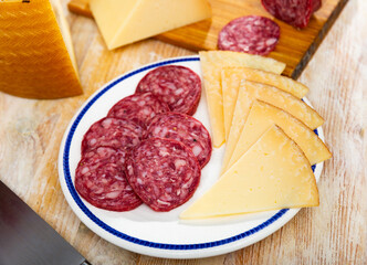 Appetizing slicing on plate, smoked sausages and pieces of hard cheese. Traditional spanish snack